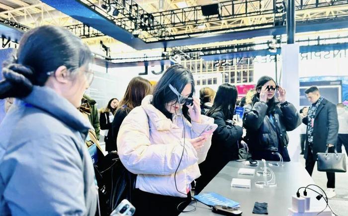 △链博会数字科技链展馆一展位前，观众正在试戴AR眼镜。